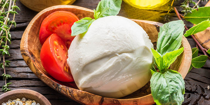 Buffalo mozzarella in the wooden bowl on the table. Food background.