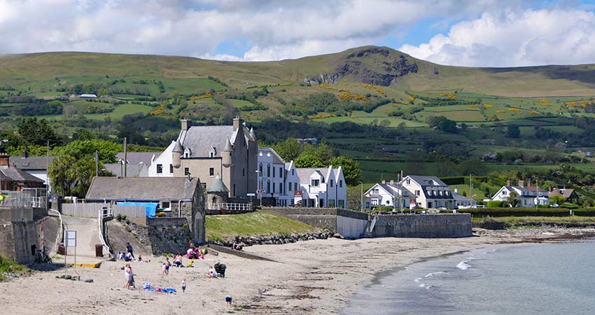 Ballygally Castle on the coast of Northern Ireland with beach and hills