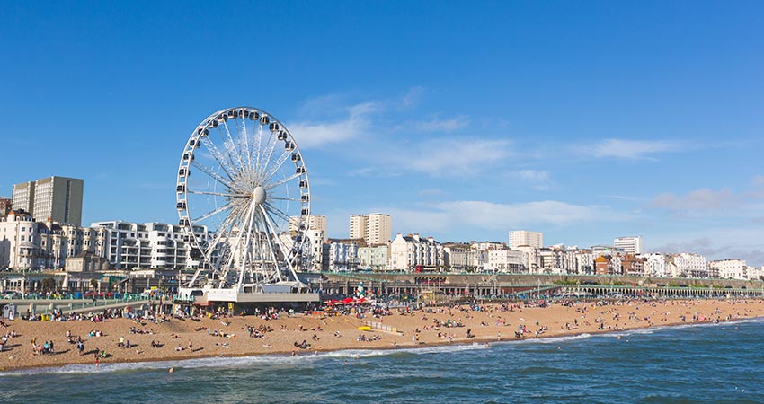 Brighton beach with Ferris wheel and city buildings along the seafront in England