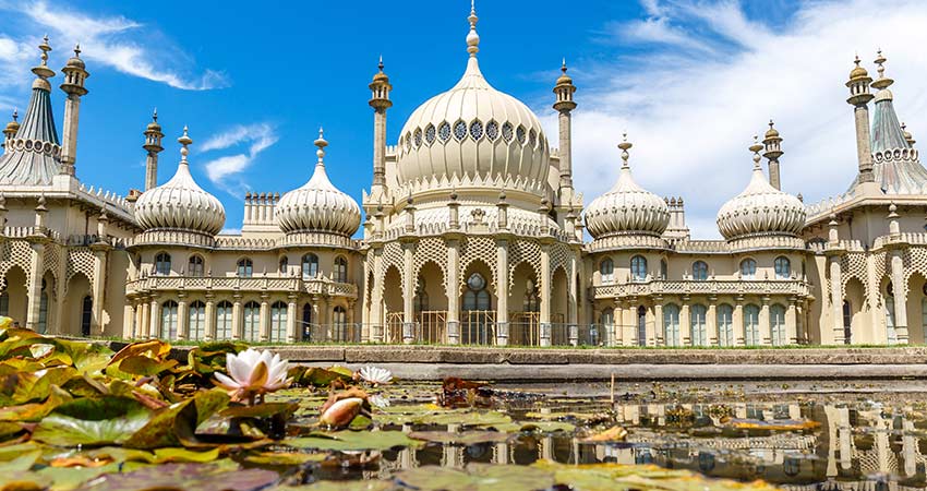 The Royal Pavilion in Brighton, England, reflected in a lily pond under a bright blue sky.