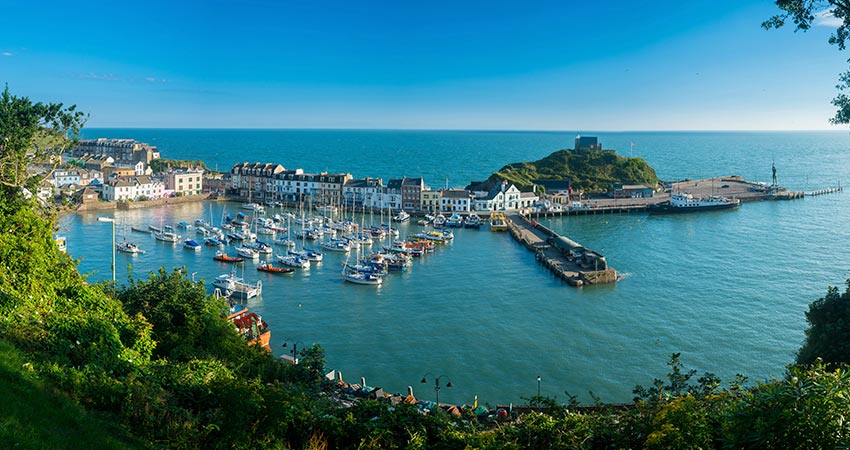 Scenic view of Ilfracombe Harbor with sailboats and coastal village in Devon, England