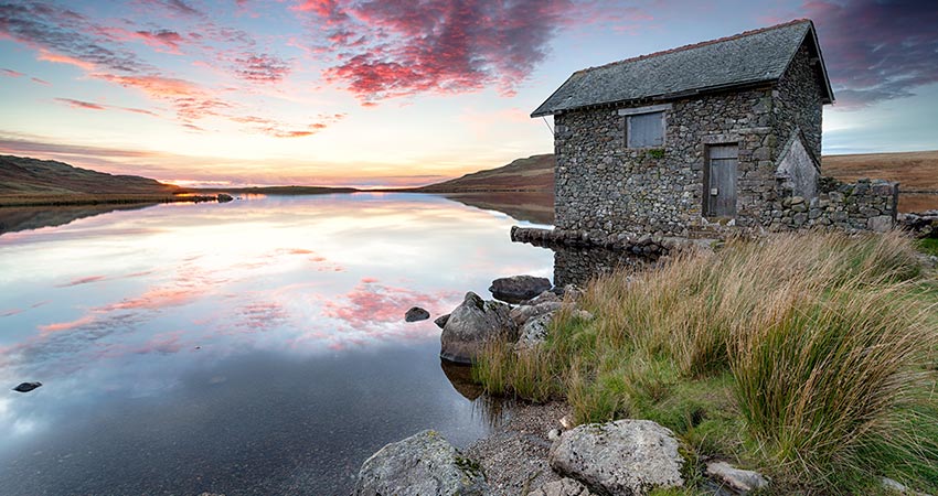 Stone boathouse on a calm lake at sunrise in the Lake District, England