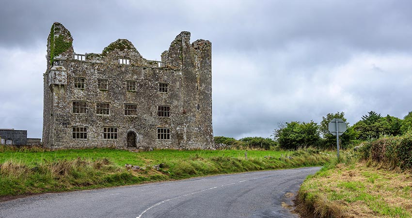 Ruins of Leamaneh Castle in County Clare, Ireland beside a rural road