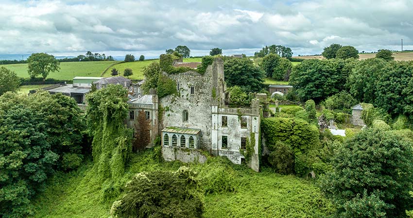 Overgrown ruins of Leap Castle in Ireland surrounded by lush greenery