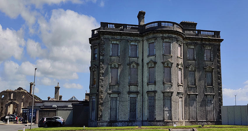 Boarded-up facade of Loftus Hall in Ireland under a blue sky

