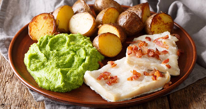 Traditional Norwegian lutefisk with peas, roasted potatoes, and crispy bacon