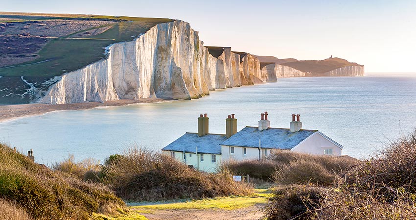White chalk cliffs and cottages overlooking the sea in South Downs National Park.