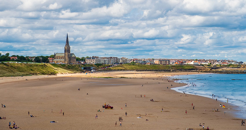 Tynemouth Longsands Beach with distant view of Tynemouth Priory and town skyline