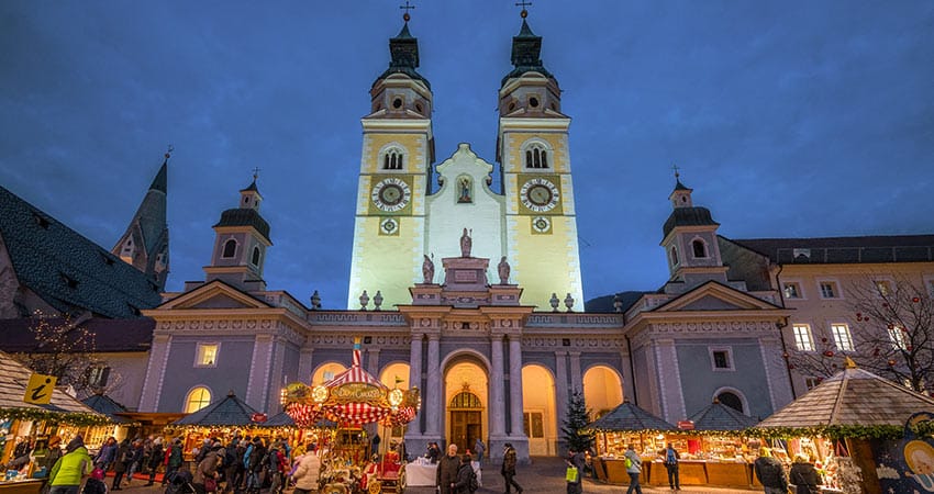 Town of Bressanone / Brixen in Italy during evening hours with Christmas market in front of church