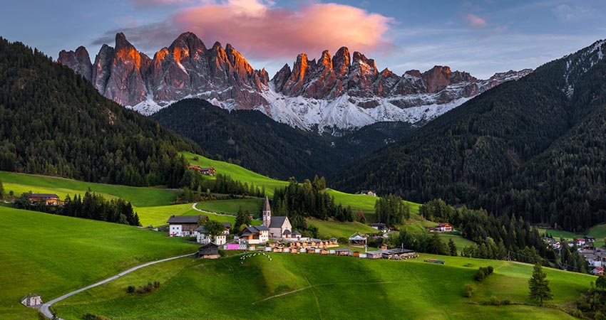 Beautiful mountain village of Santa Magdalena in Italy during sunset with Dolomite mountain range in the background