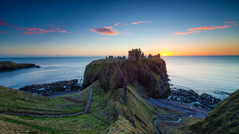 Stunning view of Dunnottar castle on top of massive hill at the edge of the ocean