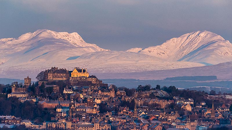 Stirling castle in the winter with snow covered mountains in the background