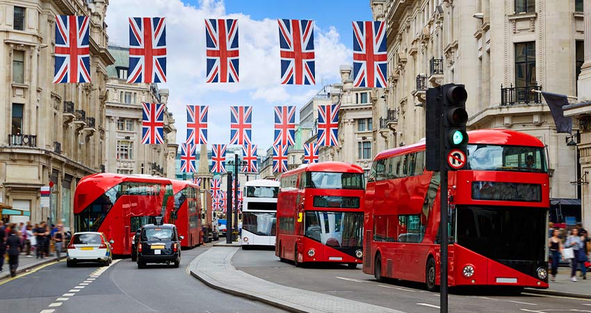 Image of busy street in London showing British flags and red London buses