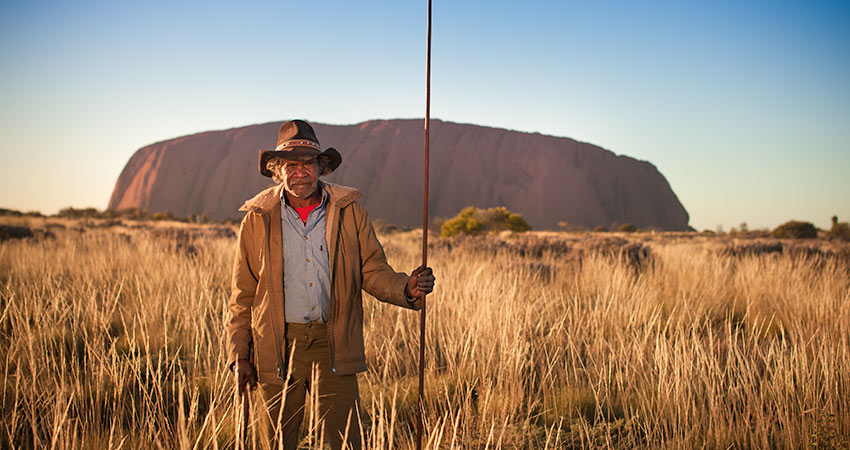 Aborigial man standing in tall dry grass in Uluru-Kata Tjuṯa National Park